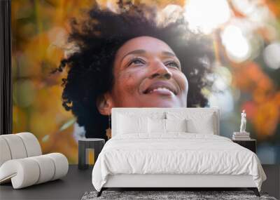 A close-up of a woman in a yoga pose, radiant smile, afro hair gently illuminated by the sun Wall mural